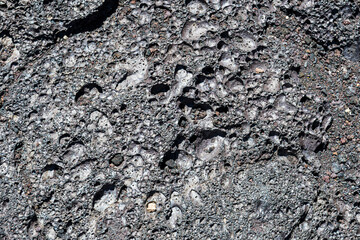 The image presents a close-up view of textured volcanic rock, showcasing unique patterns and bubbles created by natural volcanic processes, emphasizing its geological beauty.