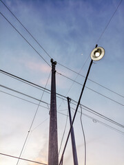 Roadside electric pole and cables against blue sky.