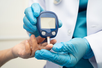 Asian doctor using digital glucose meter for check sample blood sugar level to treatment diabetes.