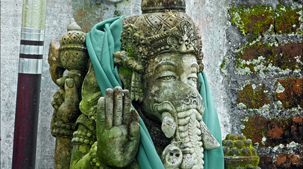 An old stone statue of Ganesha covered with moss.