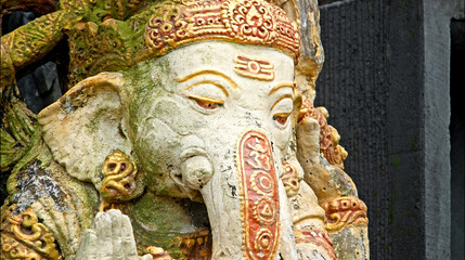An old stone statue of Ganesha covered with moss.