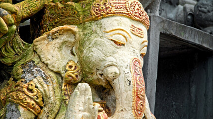 An old stone statue of Ganesha covered with moss.
