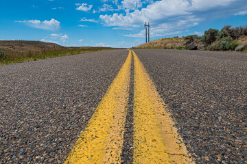 A picturesque road stretching into the distance under a vibrant blue sky, inviting exploration and adventure through a picturesque landscape.