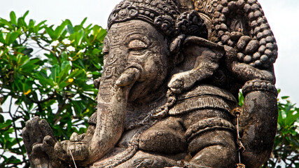 An old stone statue of Ganesha covered with moss.