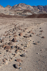 A unique composition of a desert pathway lined with vibrant rocks, capturing the essence of solitude and the rugged beauty of arid regions under a bright sky.