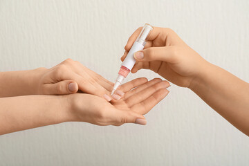 Female hands applying cuticle oil with pen on white background, closeup