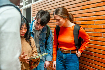 Students collaborating on tablet in university hallway
