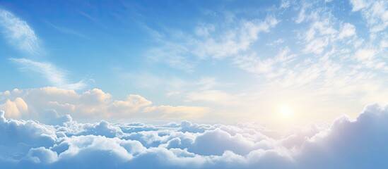 Serene sunrise over soft clouds with vibrant blue sky and golden sun rays illuminating the horizon creating a tranquil and bright atmosphere.