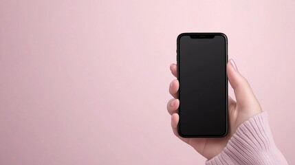 Hand holding blank smartphone against pastel pink background. Digital communication and mobile technology