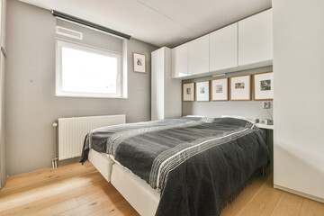 A sleek and stylish modern bedroom featuring a comfortable bed, natural light from a window, and framed artwork on the wall, showcasing minimalist design elements.
