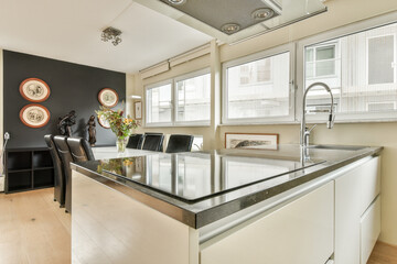 Bright and airy modern kitchen featuring sleek cabinetry and elegant dining area with large windows and decorative art.