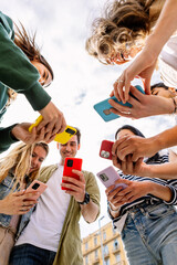 Young group of Gen Z students using mobile phone device standing together. Youth and technology...