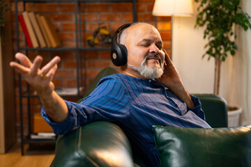 Senior man with beard wearing kurta, relaxing and enjoying music on headphones at home