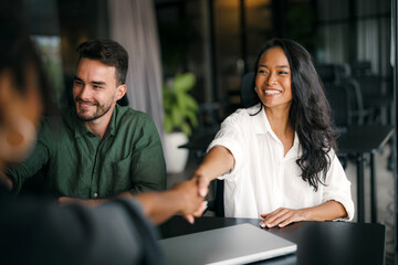 Handshake of happy young business woman and business man at office meeting