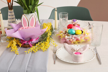 Beautiful Easter table setting with flowers, candles and painted eggs