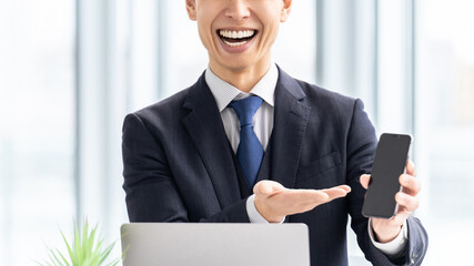 スマートフォンの画面を見せて説明する男性ビジネスマン