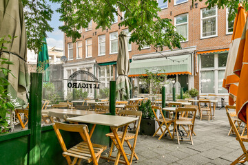 An inviting outdoor café atmosphere featuring wooden tables and chairs surrounded by lush greenery...
