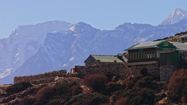 Majestic Mount Everest rising through dense clouds, revealing snow covered peaks overlooking serene Nepalese village nestled in the Shomare to Dingboche Route