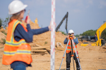 Construction surveyor or engineer working construction site leveling rod and theodolite mounted...