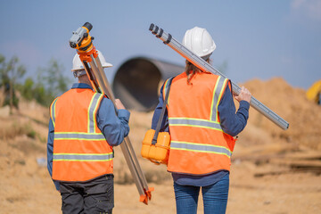 Construction surveyor or engineer working construction site leveling rod and theodolite mounted...