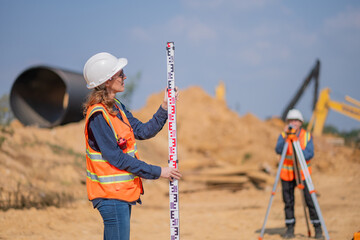 Construction surveyor or engineer working construction site leveling rod and theodolite mounted...