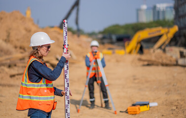 Construction surveyor or engineer working construction site leveling rod and theodolite mounted...