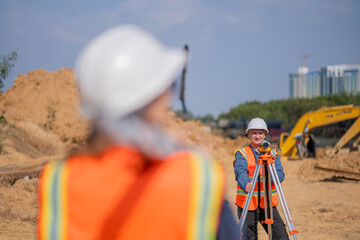 Construction surveyor or engineer working construction site leveling rod and theodolite mounted...