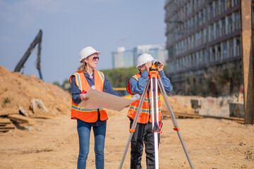 Construction surveyor or engineer working construction site blueprint and theodolite mounted tripod...