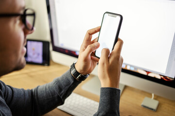Cropped picture of young man holding cellphone in hands and typing on it.