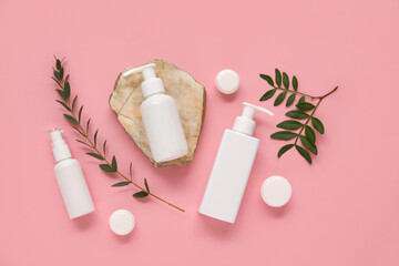 Composition with bottles and jars of cosmetic products on pink background