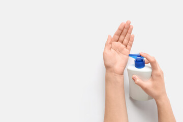 Female hands with bottle of sanitizer on white background