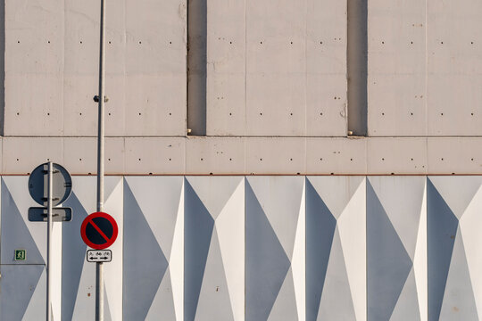 Concrete facade with geometric triangular patterns and urban signage details.