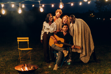 Friends enjoying music and campfire at night