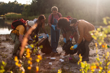 Volunteers cleaning up litter in nature at sunset