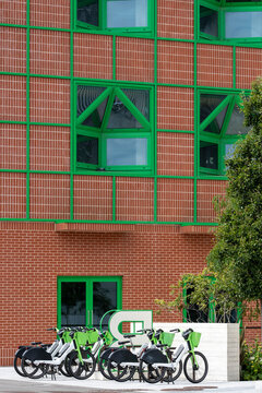 Red brick residential building with bold green geometric window frames, London.