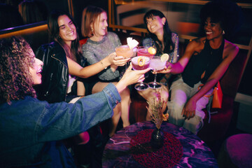 Group of friends toasting cocktails in a lively and stylish nightlife setting