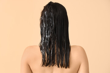 Beautiful young woman with hair mask on beige background, back view