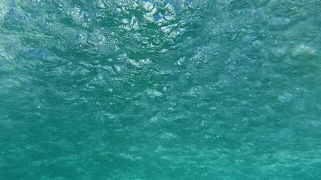 The seething surface of the water below waterfall, waterdrops falling on water surface, Underwater shot, Bottom view, Slow motion