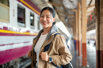 Fototapeta premium The Beautiful Asian woman is smiling and posing to the camera at train station.