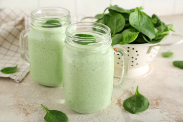 Mason jars of fresh spinach smoothie on white table