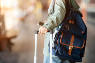 A close up of the hand dragging a luggage while walking away in the empty train station.