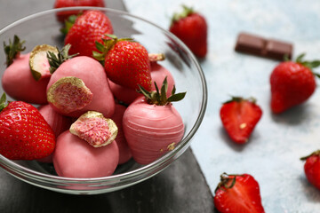 Glass bowl with chocolate covered strawberries and fresh berries on light blue background