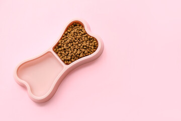Bone shaped bowl with dry pet food on pink background