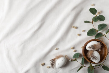 Delicate easter composition with decorative eggs in the wooden bowl with branches of eucalyptus.  Happy Easter concept, copy space for your text.