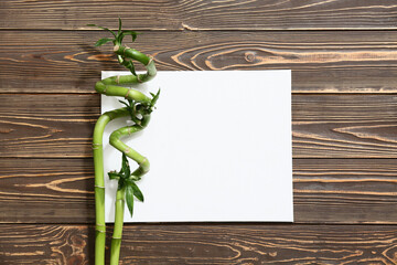 Blank card with green bamboo stems on wooden background