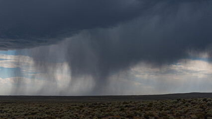 This dramatic image captures rain cascading down over an arid landscape, highlighting the contrast between dryness and moisture while emphasizing the beauty of nature's cycles.