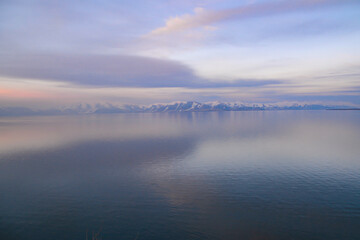 Beautiful sunset over the lake. Sunrise on the sea. Beautiful landscape with lake, mountains and sunset. Reflection in the water