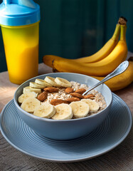 Protein Oatmeal Bowl with Banana Slices and Almonds, Served with a Yellow Shaker and Ripe Bananas