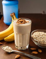 Creamy Banana Oatmeal Protein Smoothie with Almonds in a Glass on a Wooden Table