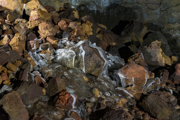 An intriguing close-up of a rocky floor featuring flowing water and vibrant mineral deposits, illustrating the dynamic processes of nature and geological beauty.